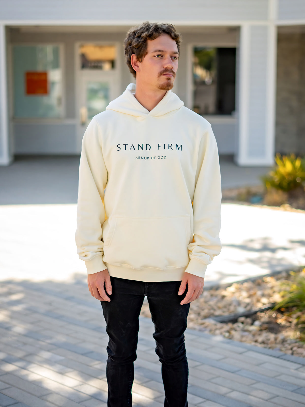 Model wearing cream Yahweh hoodie with Stand Firm chest print
