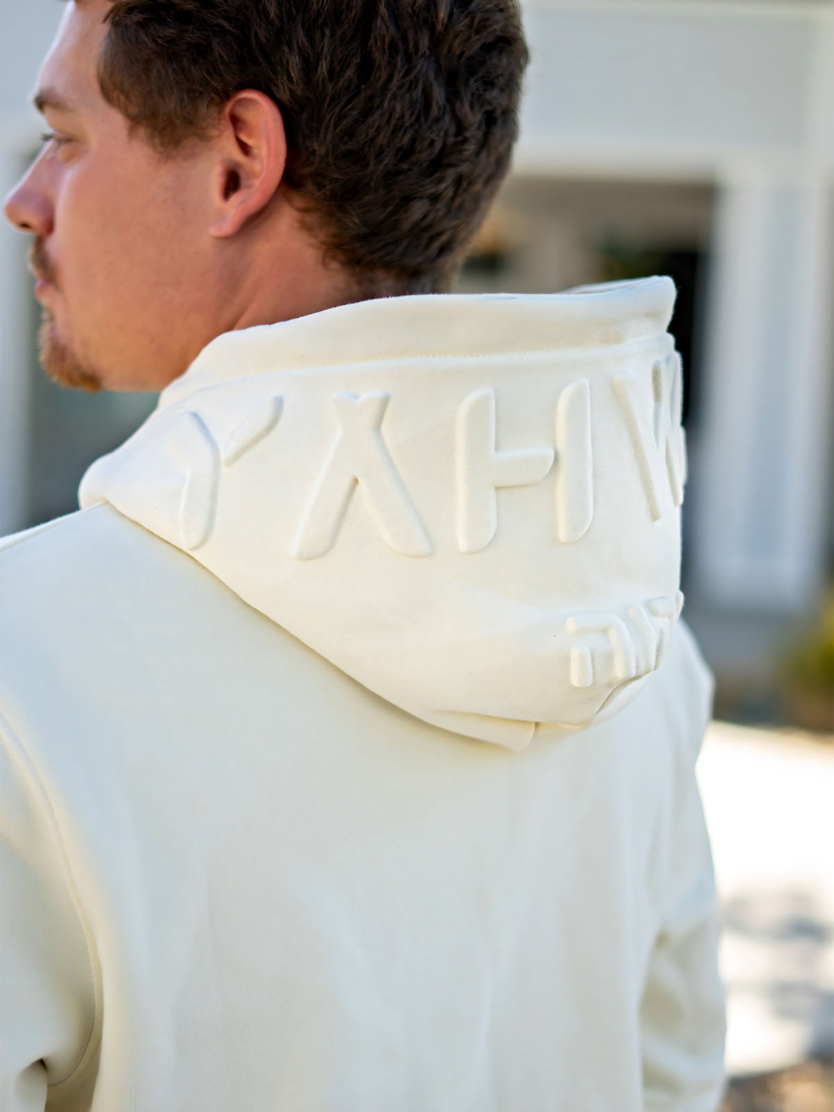 Model wearing cream Yahweh hoodie with Stand Firm chest print